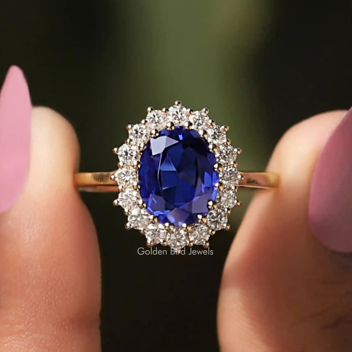 Front View Of Sapphire Blue Oval Cut Halo Engagement Ring In a Two Fingers