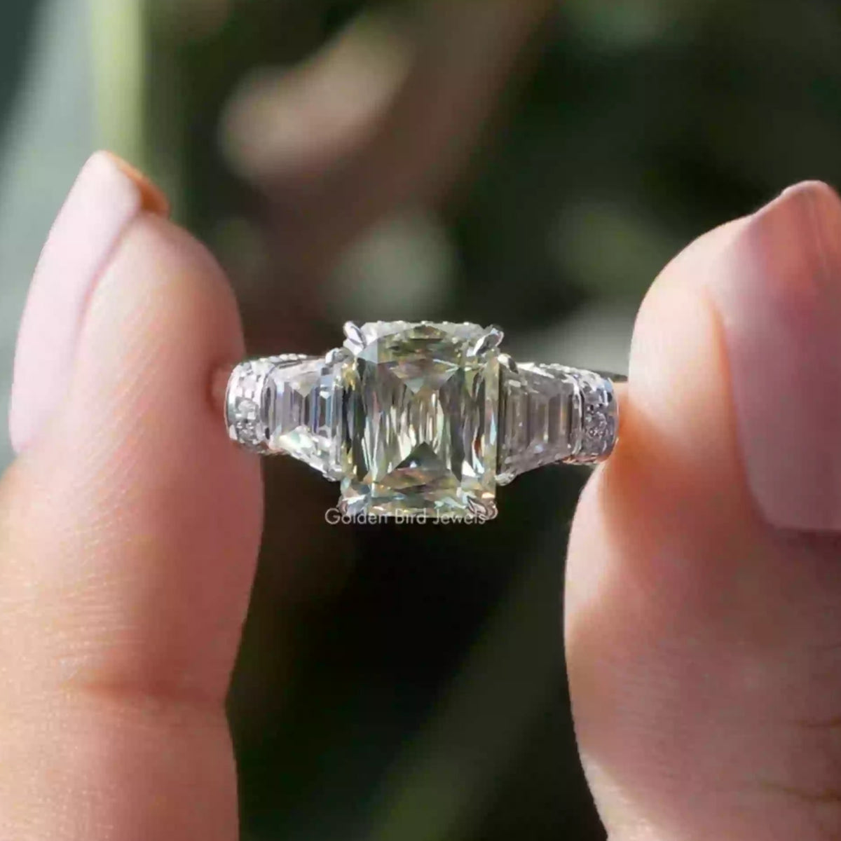 Two fingers holding the Criss Cut Moissanite Three Stone Ring