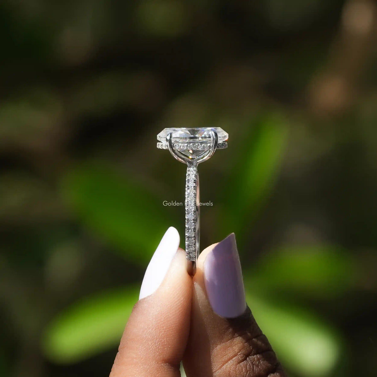 Side View of Halo Oval Cut Moissanite White Gold Ring In two fingers