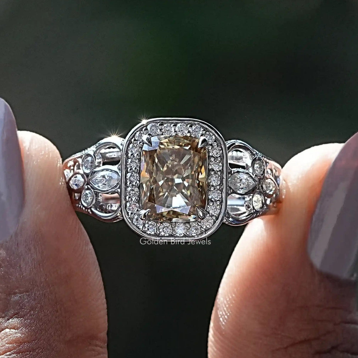 Two fingers holding the Cushion Cut Moissanite Halo Engagement Ring