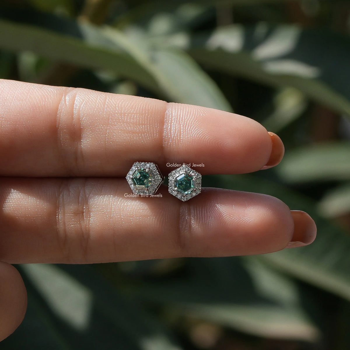 In two-finger view of halo moissanite stud earings