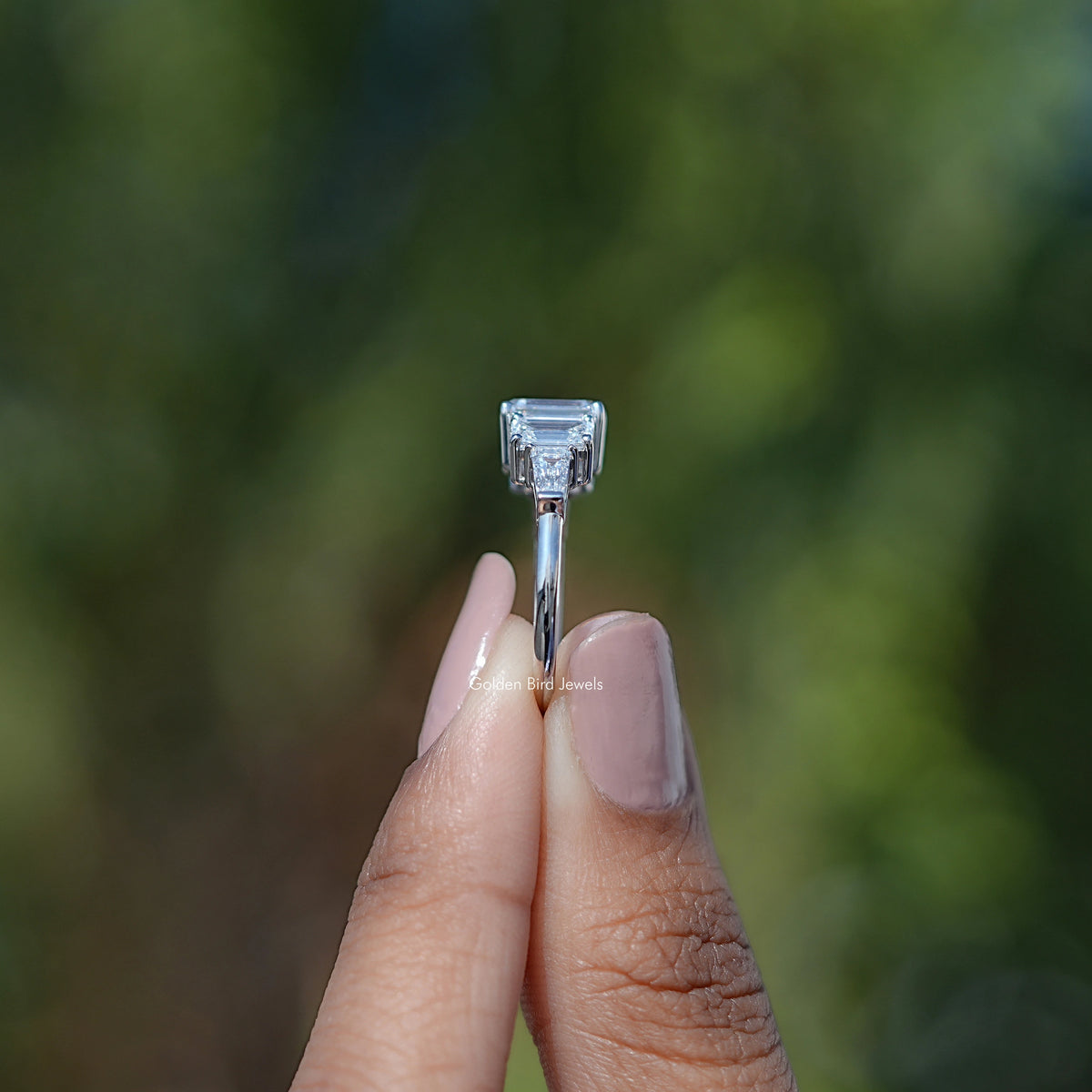 Side View of Emerald Cut Diamond Five Stone Ring In two fingers