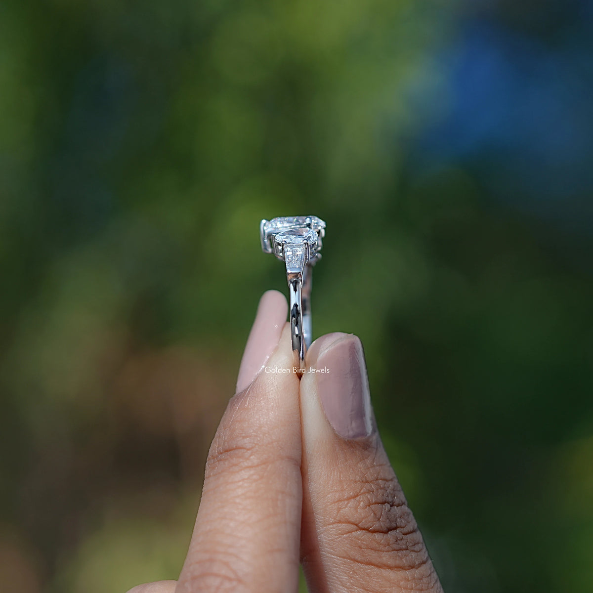 Side View of Pear Cut Lab Diamond Five Stone Ring In two fingers