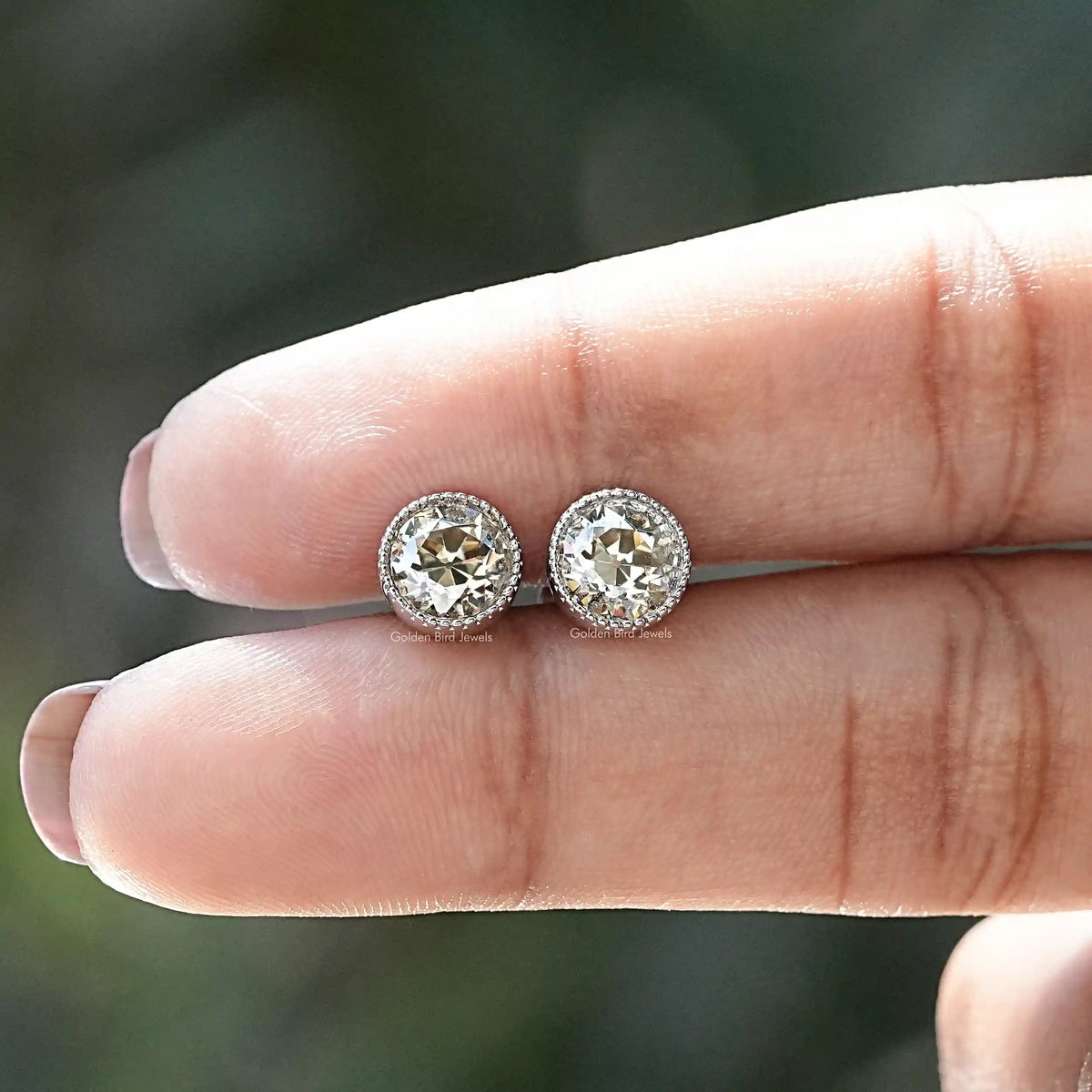 In two-finger view of moissanite studs in European cut