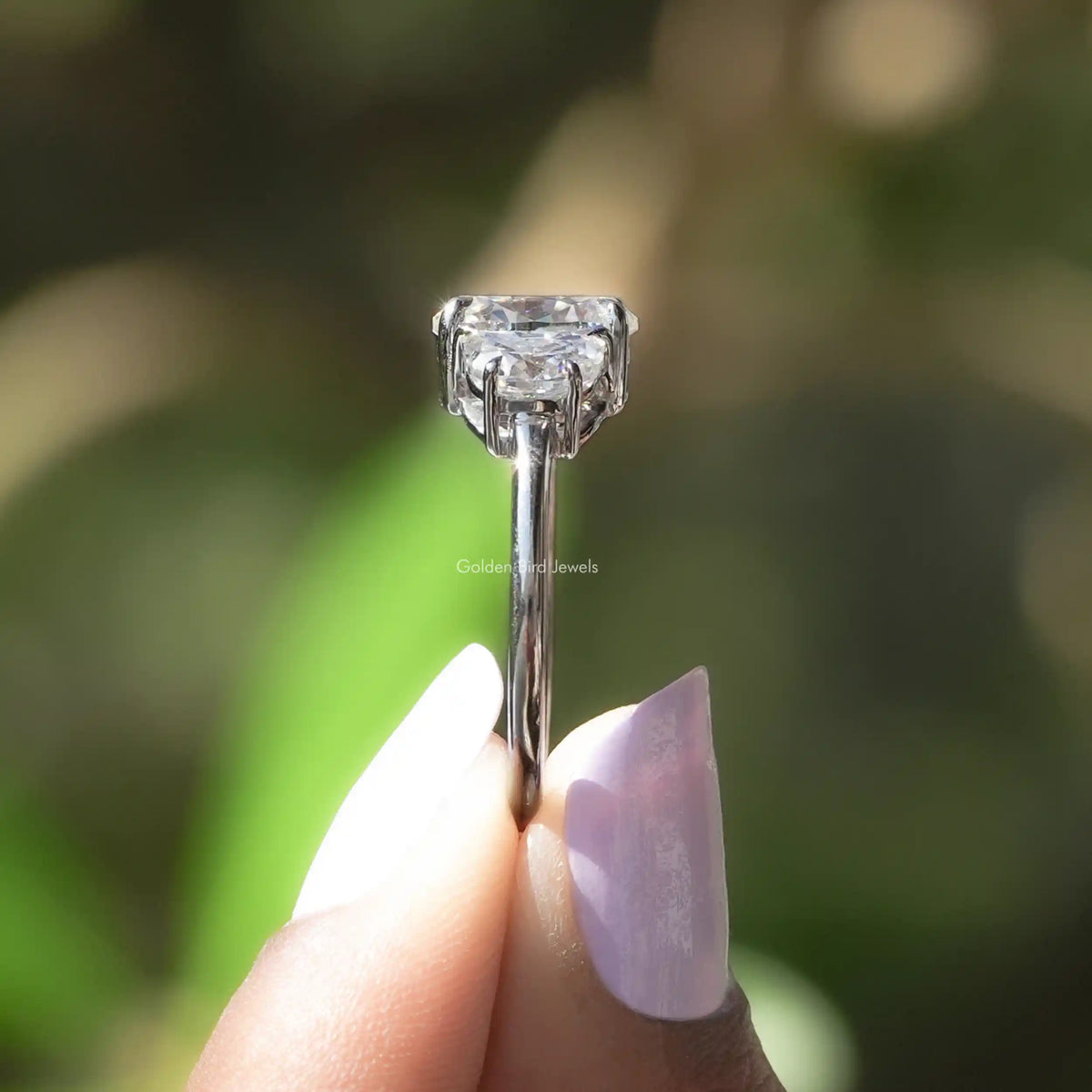 Side View of Oval Cut And Half Moon Cut Three Stone Ring In two fingers