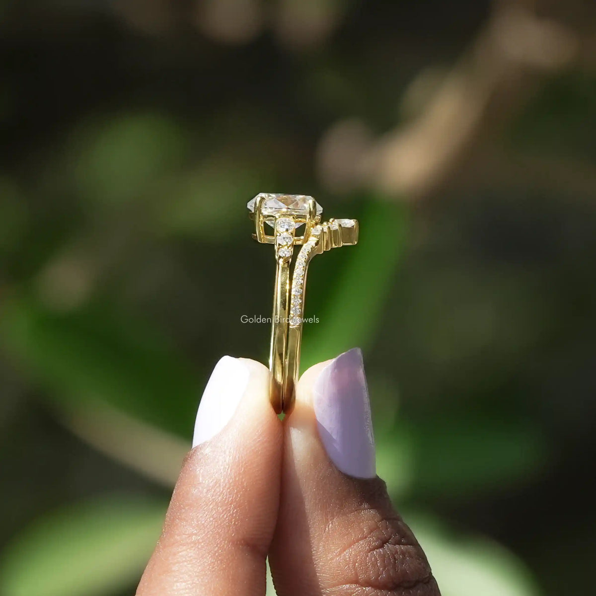 Side View of Oval Cut Accent Stone Moissanite Ring In two fingers