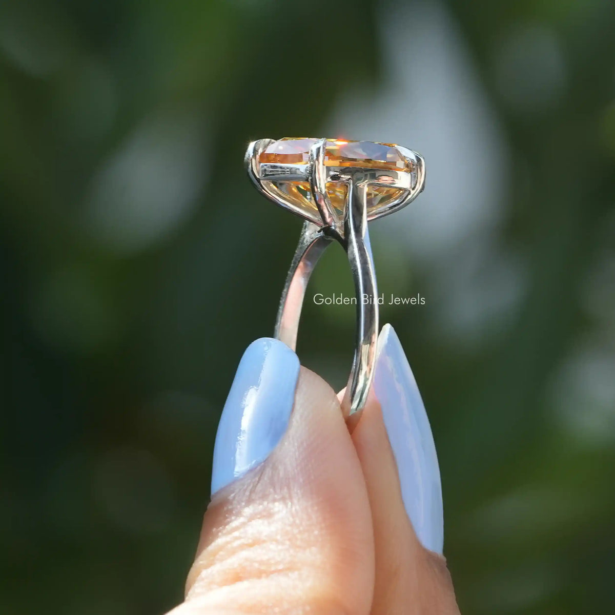 Side View of Pear Cut Moissanite Engagement ring In two fingers