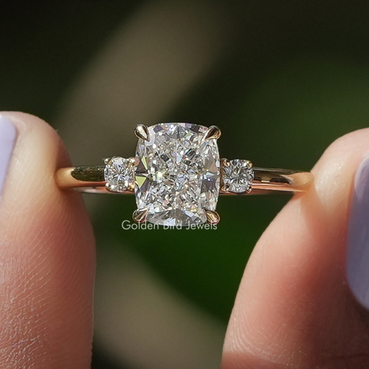 Cushion Cut Diamond Three Stone Wedding Ring held between fingers