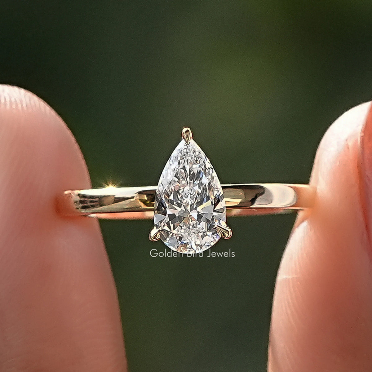 Pear Shaped Lab Diamond Solitaire Engagement Ring Held Between Fingers