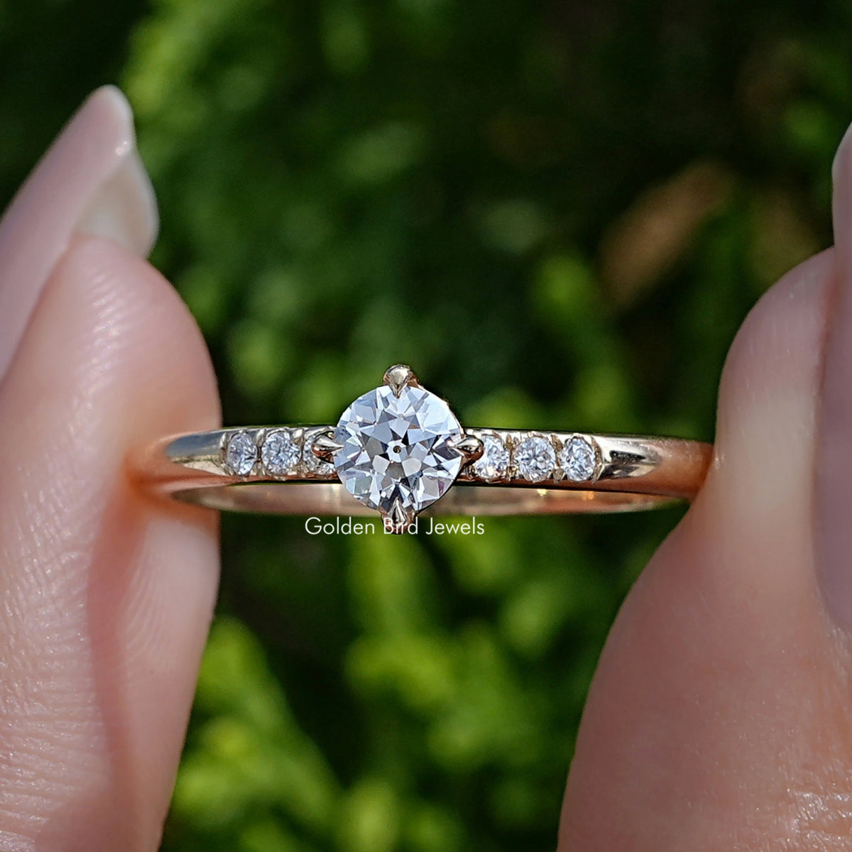Old European Round Cut Lab Diamond Accent Ring Held Between Fingers