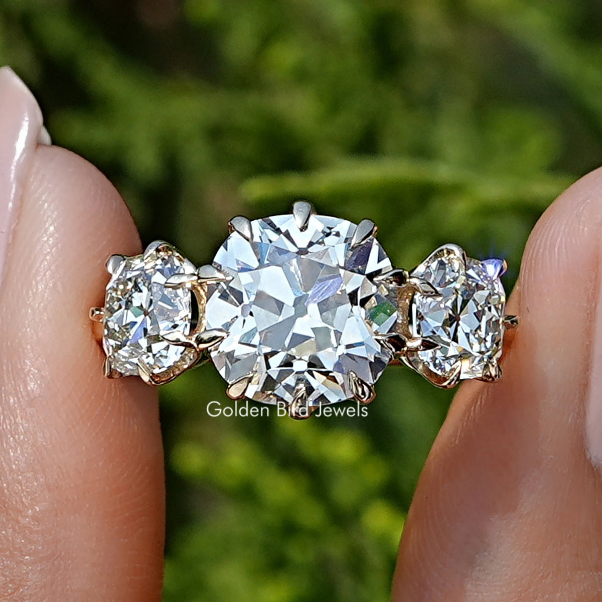 Square Old Mine Cushion Diamond Three Stone Ring Held Between Fingers