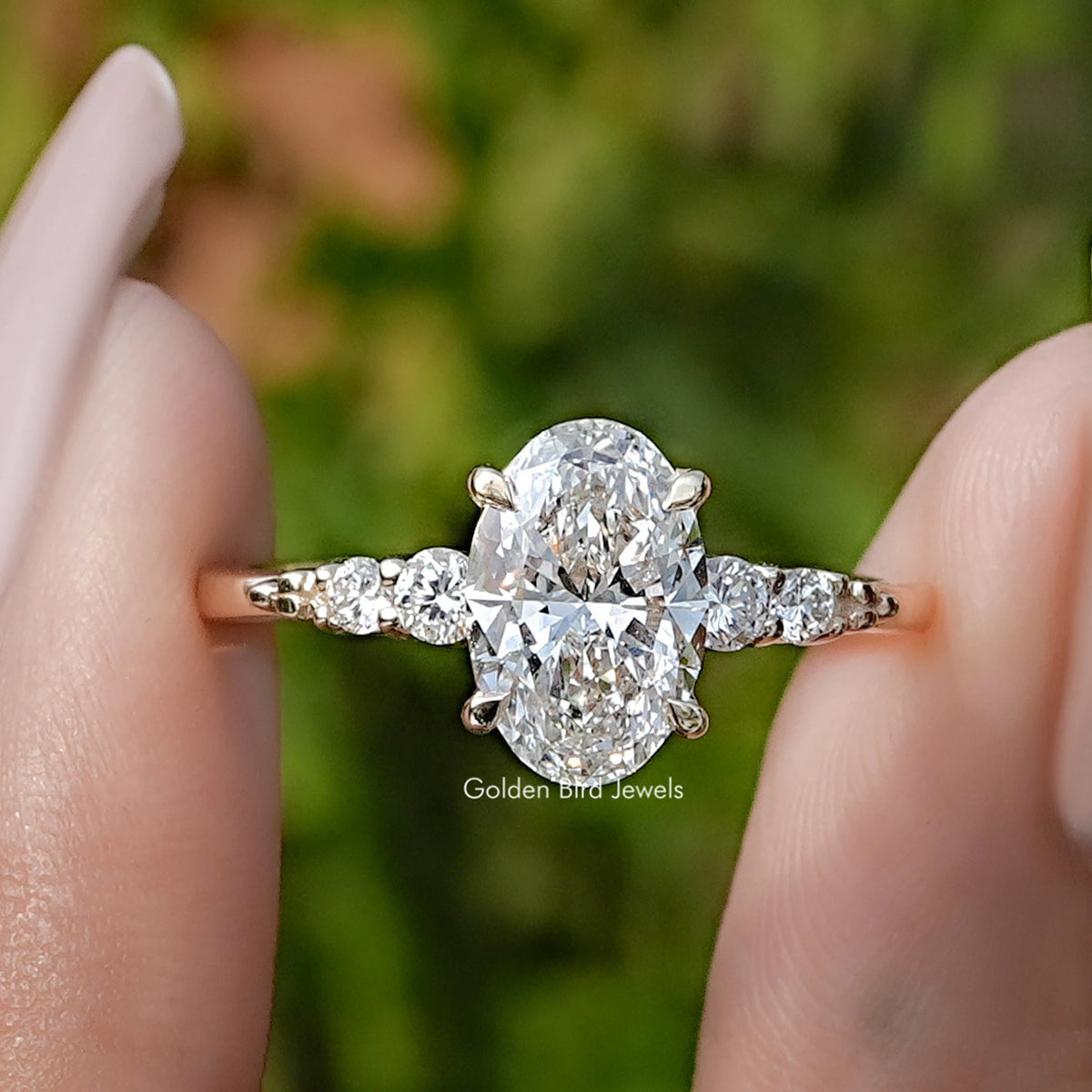 Oval And Round Cut Lab Diamond Five Stone Ring Between Fingers