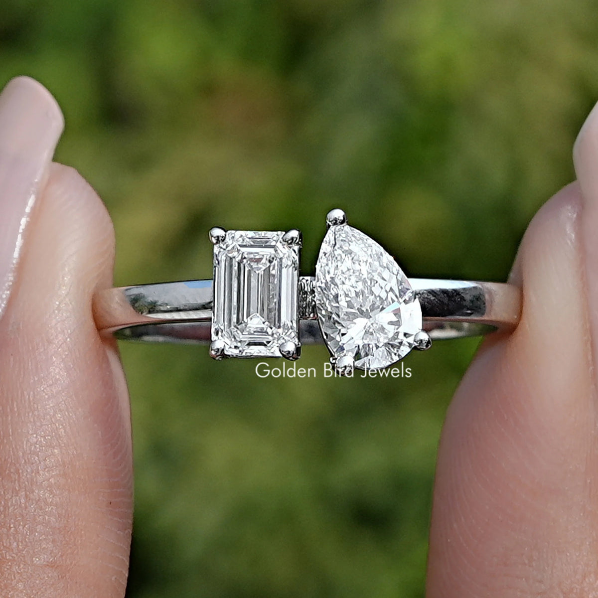 Emerald and Pear Lab Diamond Toi Et Moi Ring Held Between Fingers