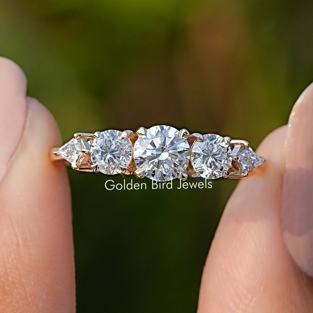 Kite And Round Cut Lab Diamond Five Stone Ring Held Between Fingers