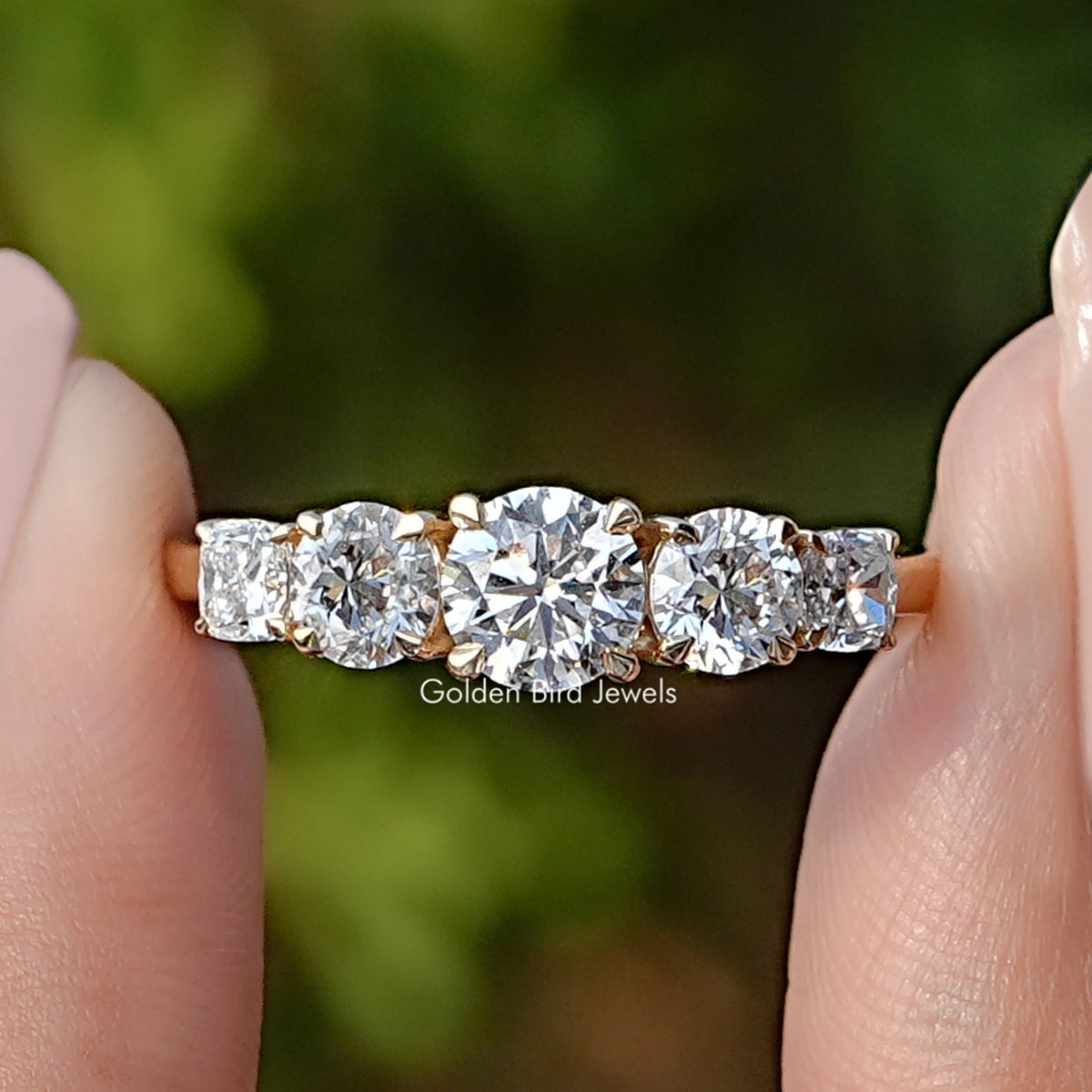 Round Cut Lab Diamond Five Stone Ring Held Between Fingers