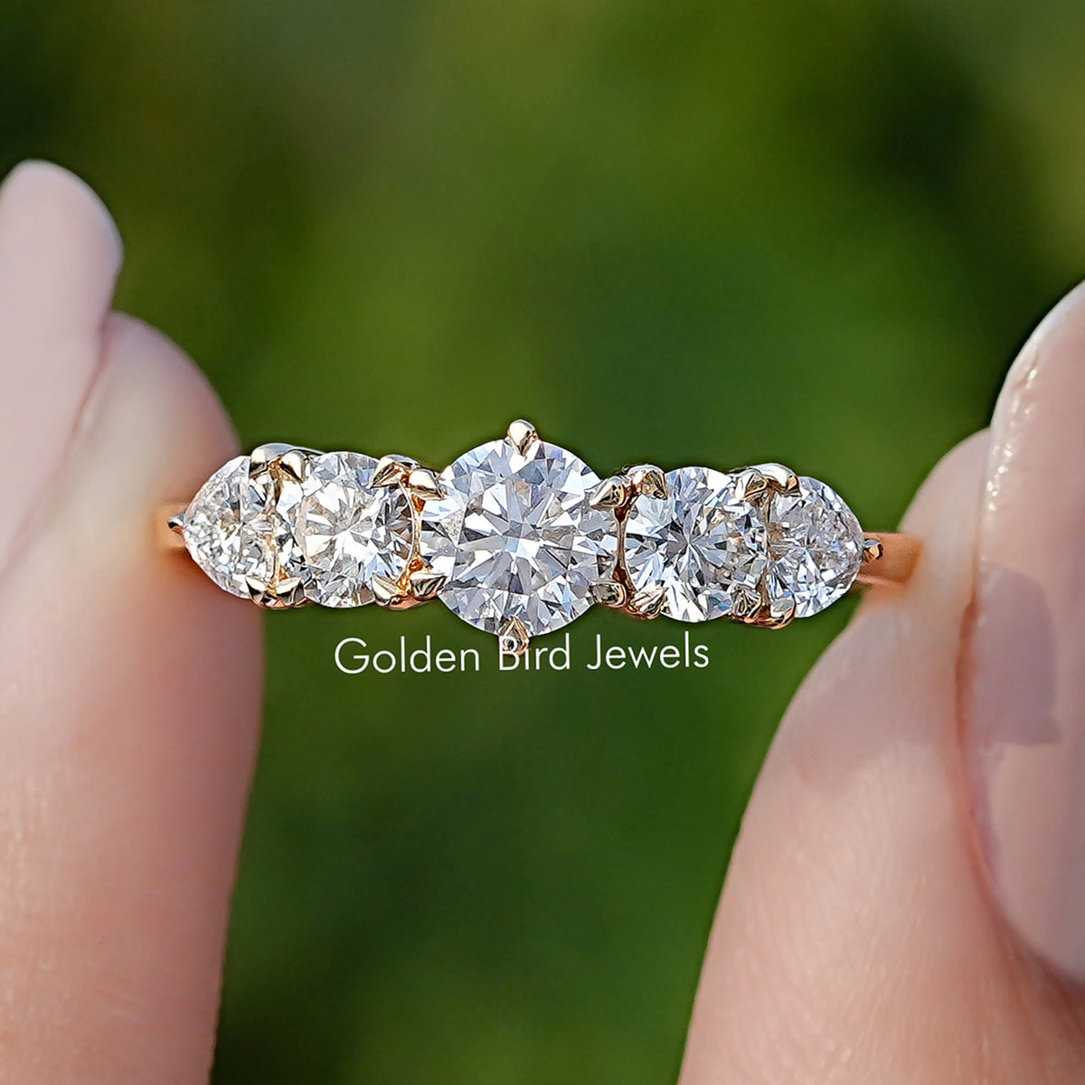 Heart And Round Cut Lab Diamond Five Stone Ring Held Between Fingers