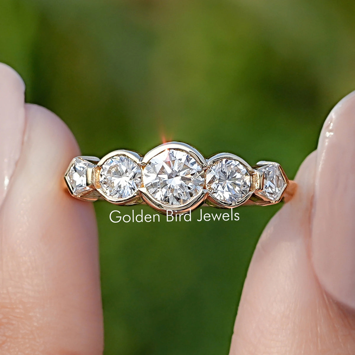 Pentagon And Round Cut Lab Diamond Five Stone Ring Held Between Fingers