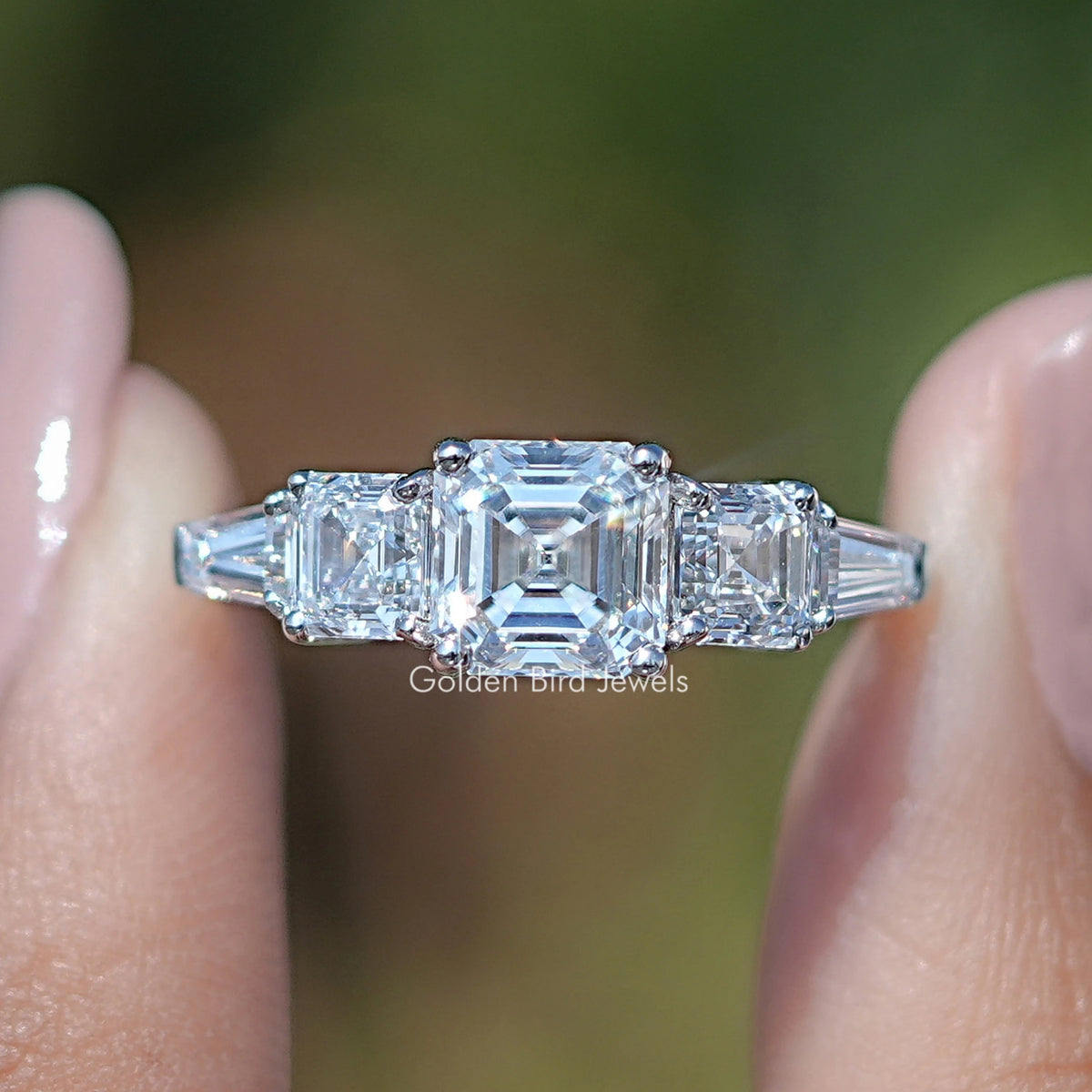 Asscher And Tapered Baguette Cut Five Stone Ring Held Between Fingers