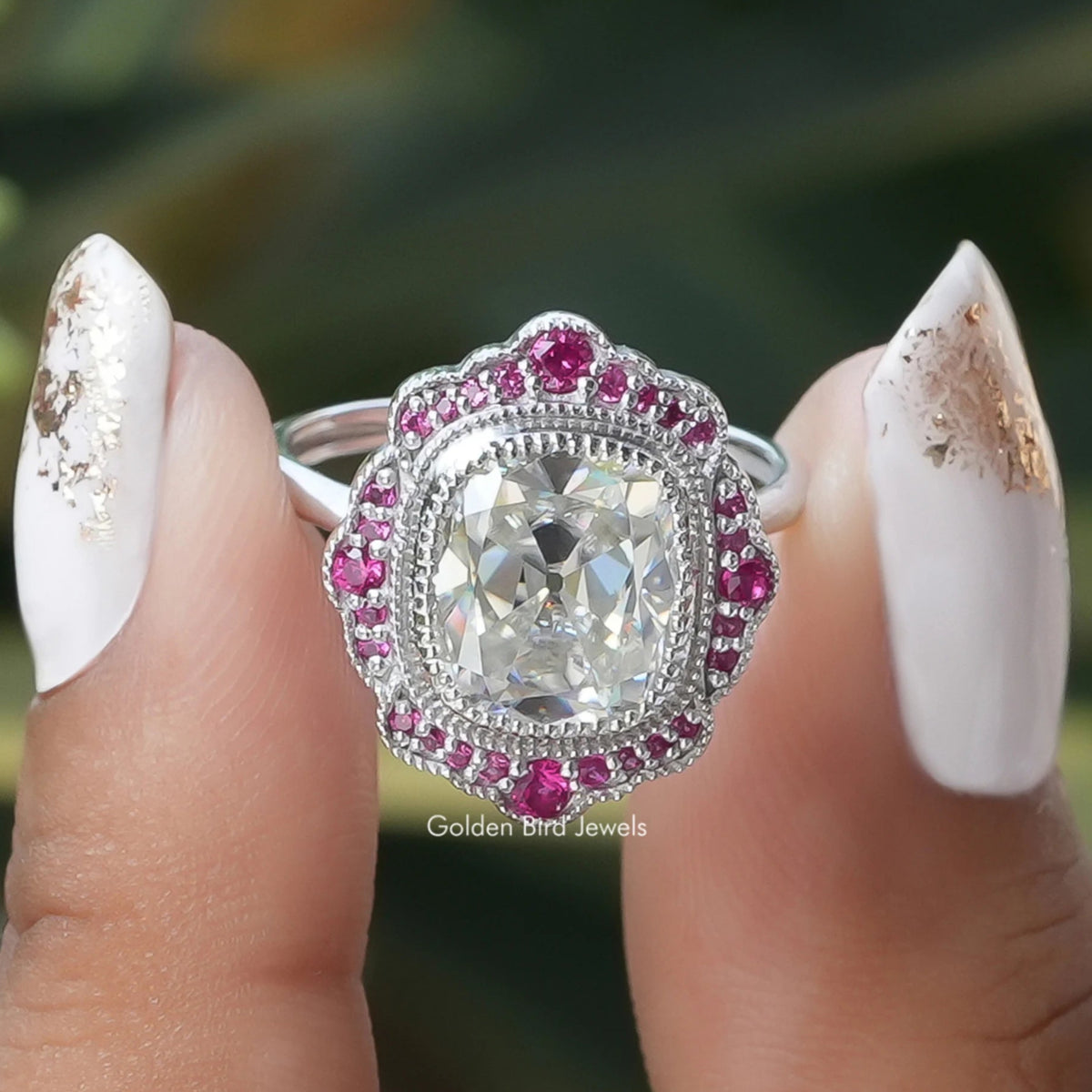 Two fingers holding the Old Mine Cushion Cut Moissanite Halo Ring