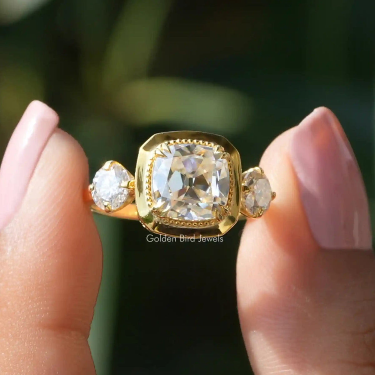 Two fingers holding the Old Mine Cushion Cut Moissanite Ring