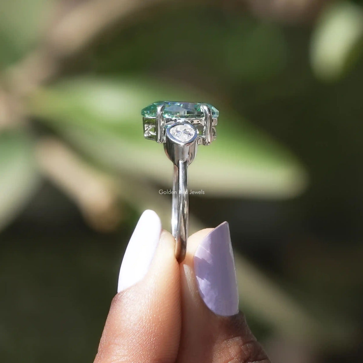 Side View of Pear Cut Moissanite Three Stone Ring In two fingers