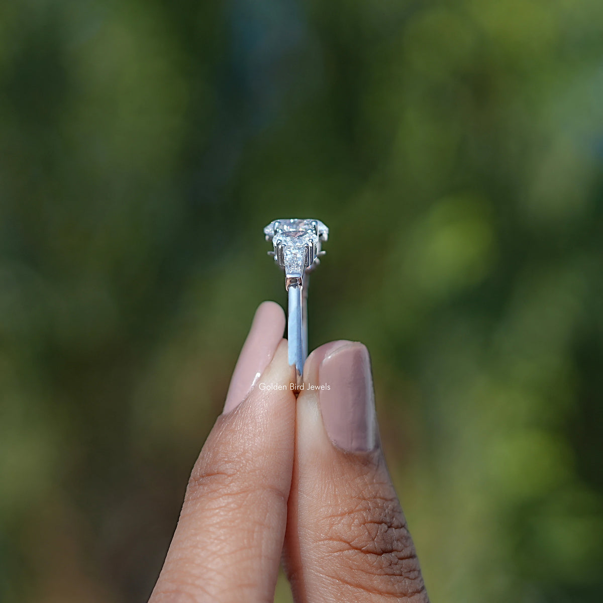 Side View of Oval And Tapered Baguette Lab Diamond Five Stone Ring In two fingers