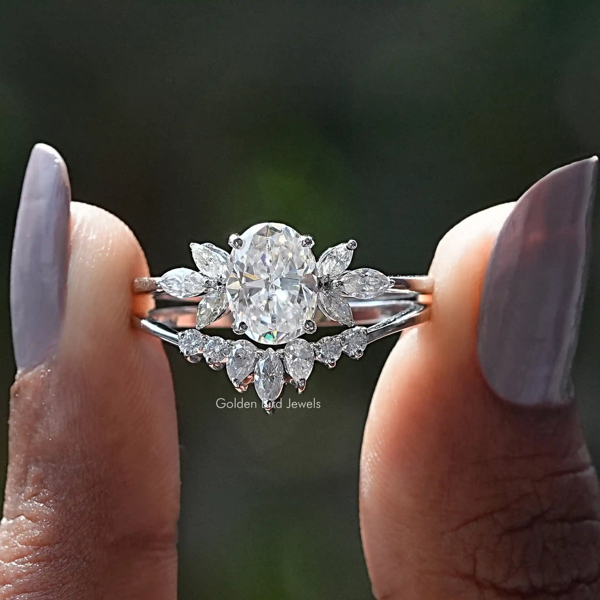 Two fingers holding the Oval And Marquise Cut Cluster Moissanite Ring