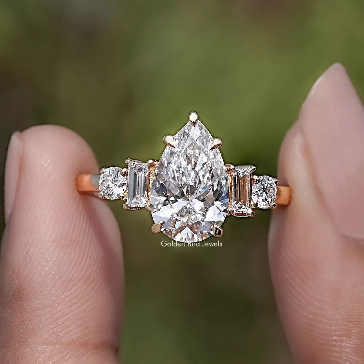 Pear And Baguette Cut Lab Diamond Five Stone Ring Between Two Fingers