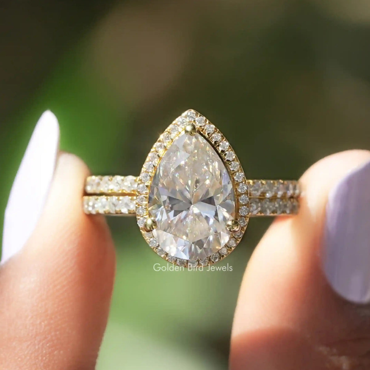 Two fingers holding the Pear Cut Moissanite Engagement Ring