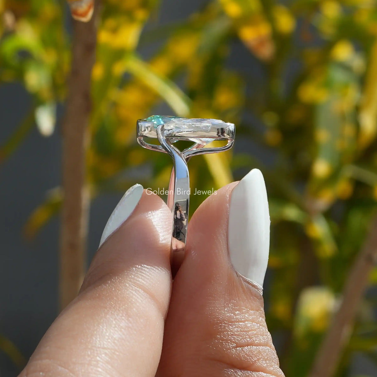 Close up view of a women’s halo engagement ring holding on two fingers