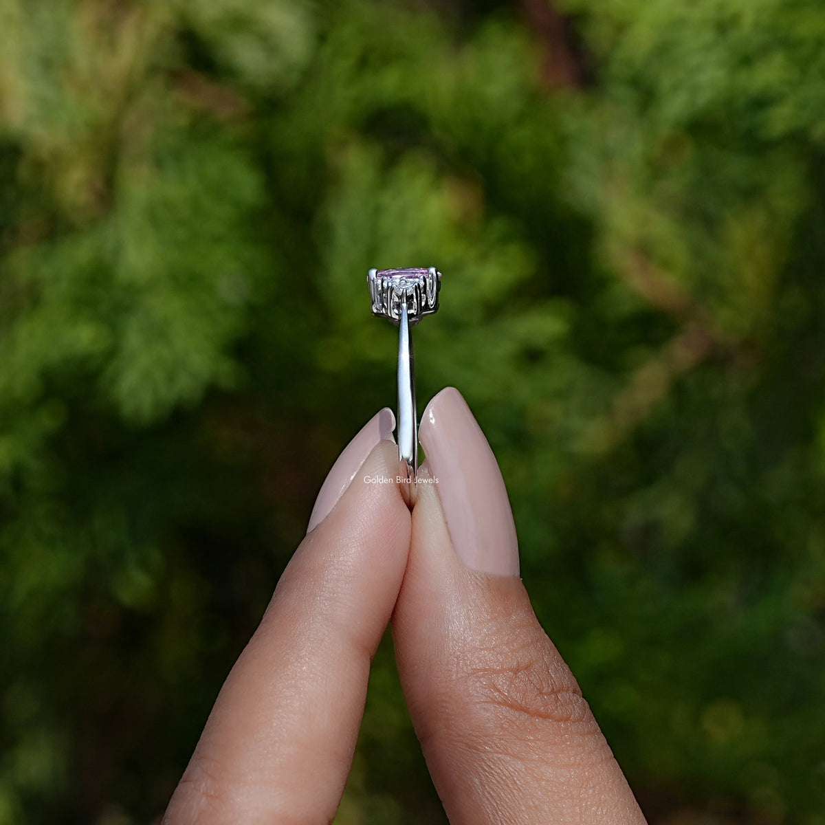 Side View of Oval Cut Gemstone Engagement Ring In two fingers