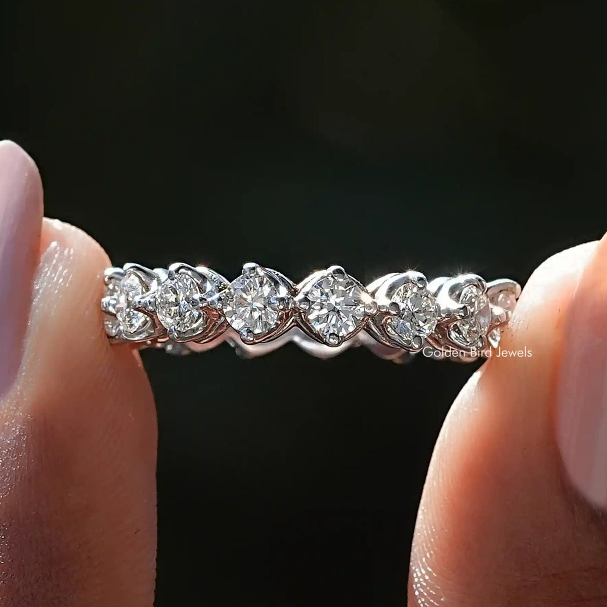 Round Cut Lab Diamond Eternity Wedding Band Held Between Fingers