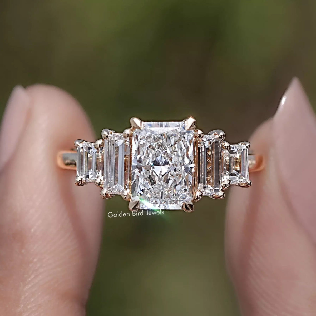 Radiant And Baguette Lab Diamond Five Stone Ring Held Between Two Fingers