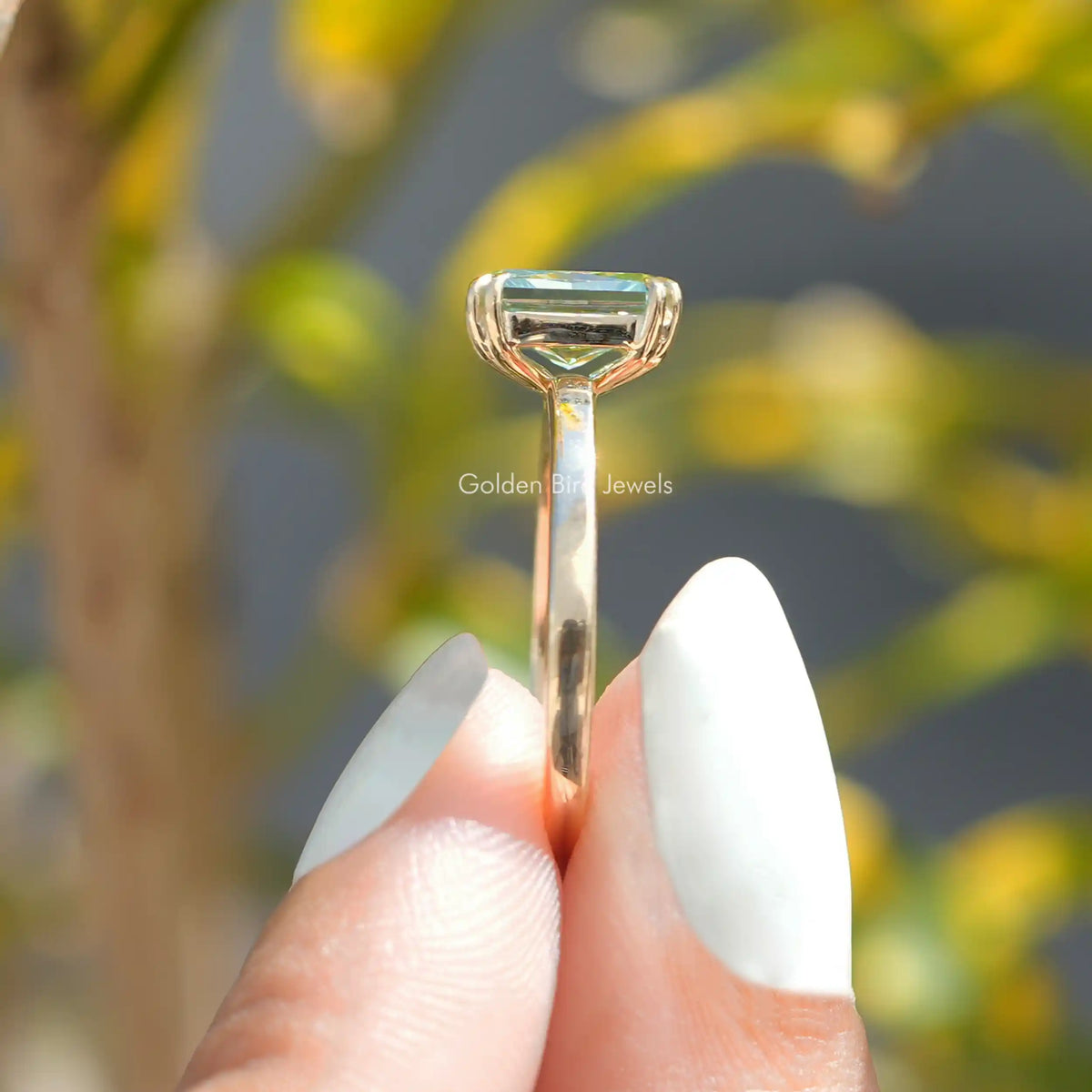 Side Stone View A Radiant Cut Engagement Ring In a two fingers