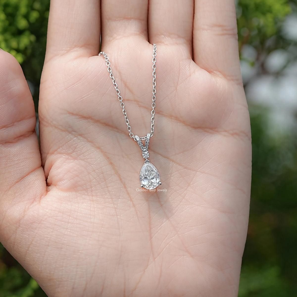 In hand Showing View Of Round And Pear Cut Moissanite Tear Drop Pendant