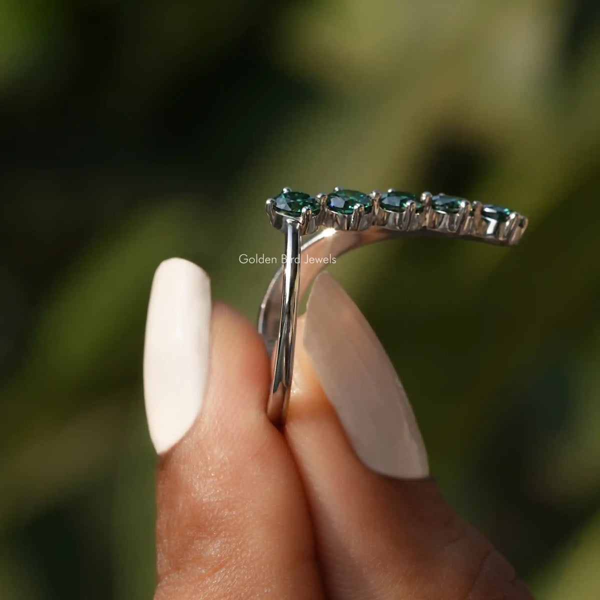 Side View of Green Round Cut V Shaped Engagement Ring In two fingers
