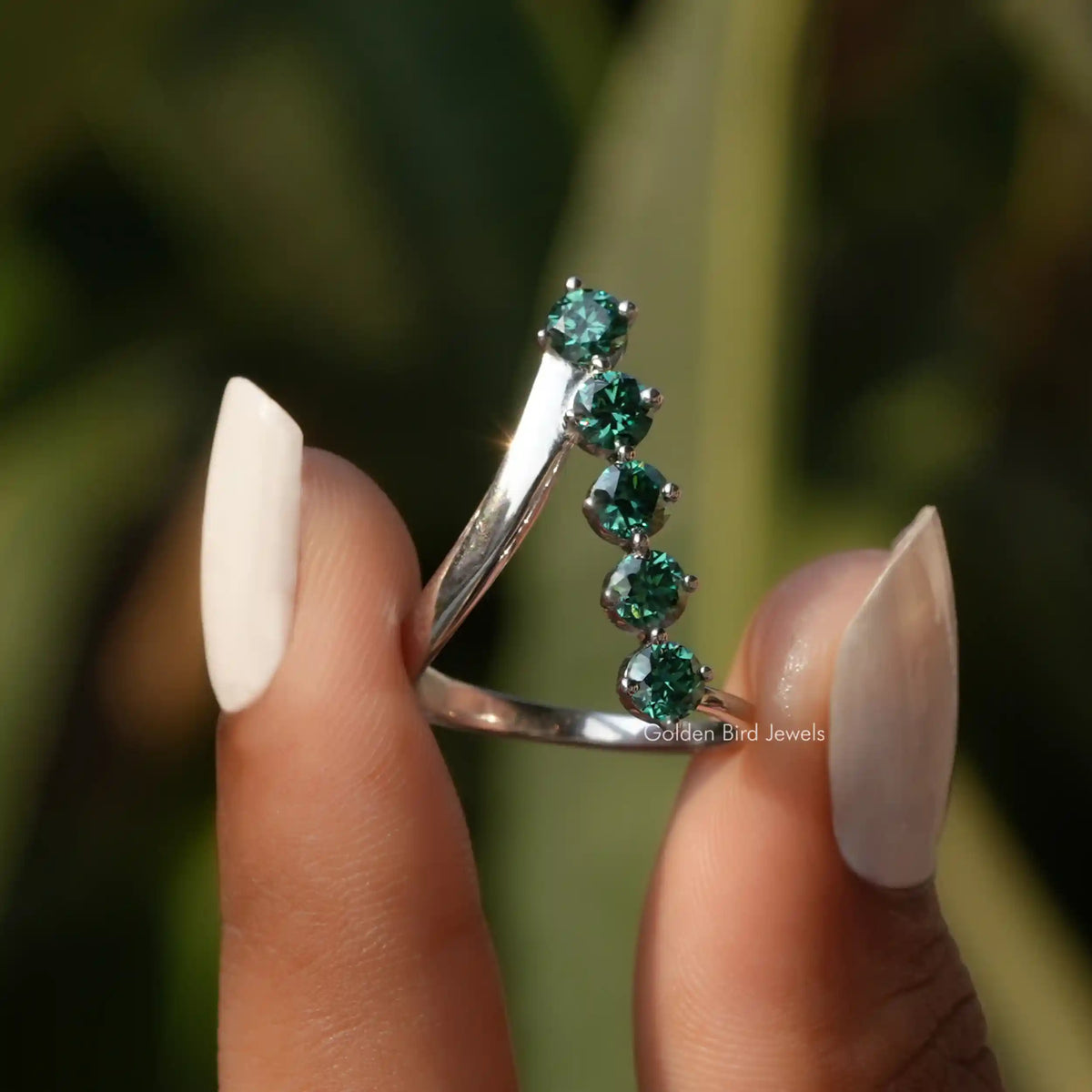 Two fingers holding the Round Cut V Shaped Moissanite Ring