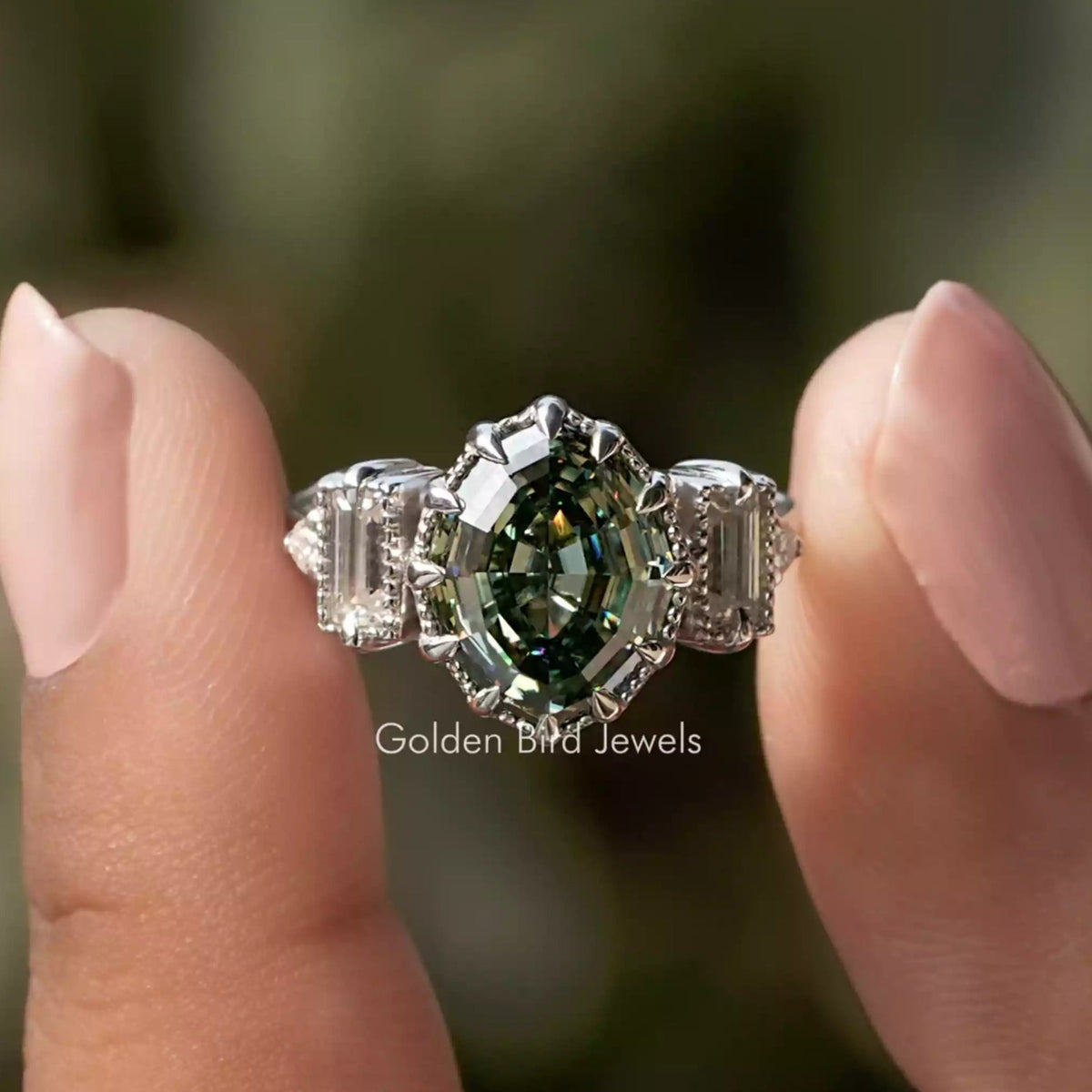 Two fingers holding the Step Cut Oval And Baguette Engagement Ring