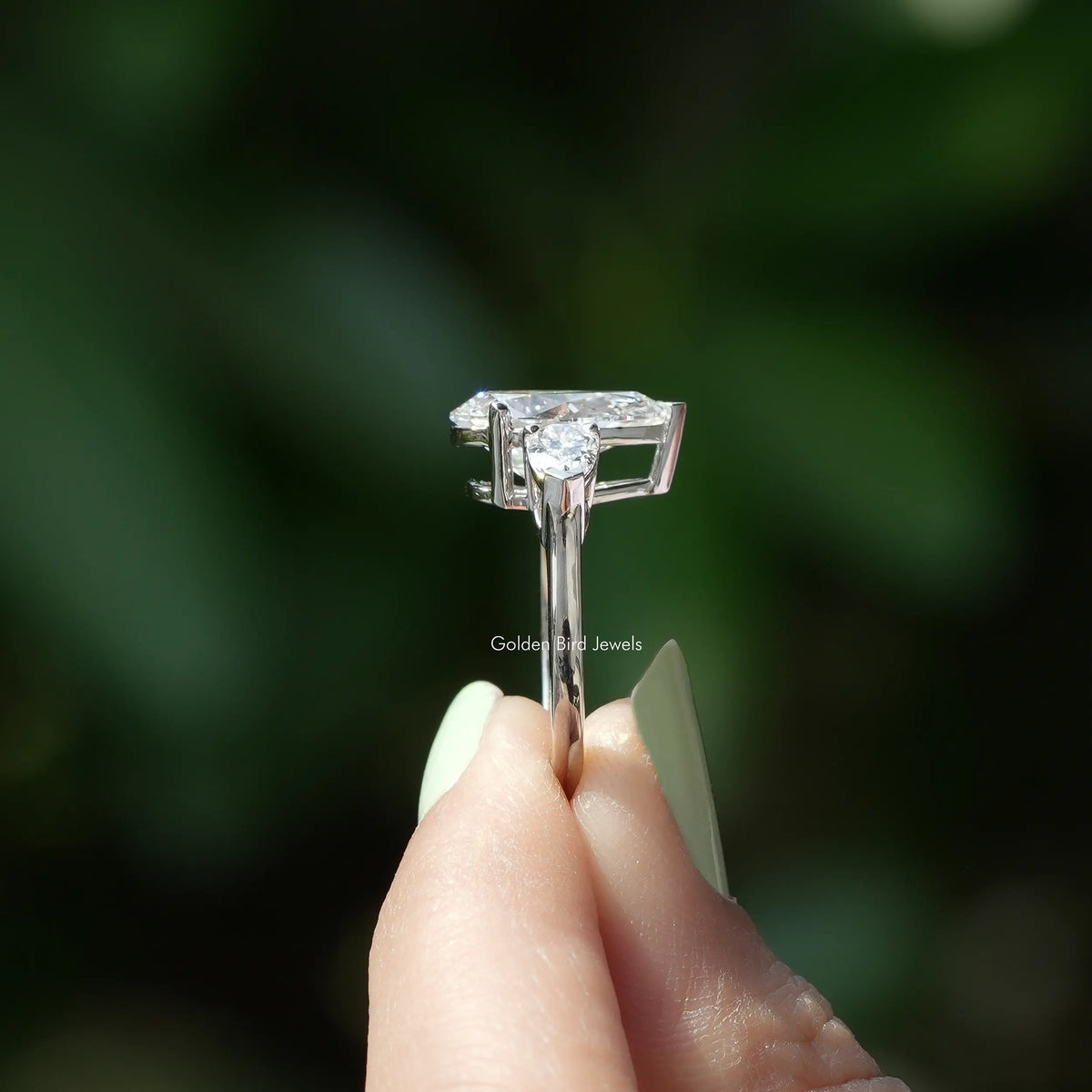 Side View of 3 Stone Pear Cut Diamond Engagement Ring In two fingers