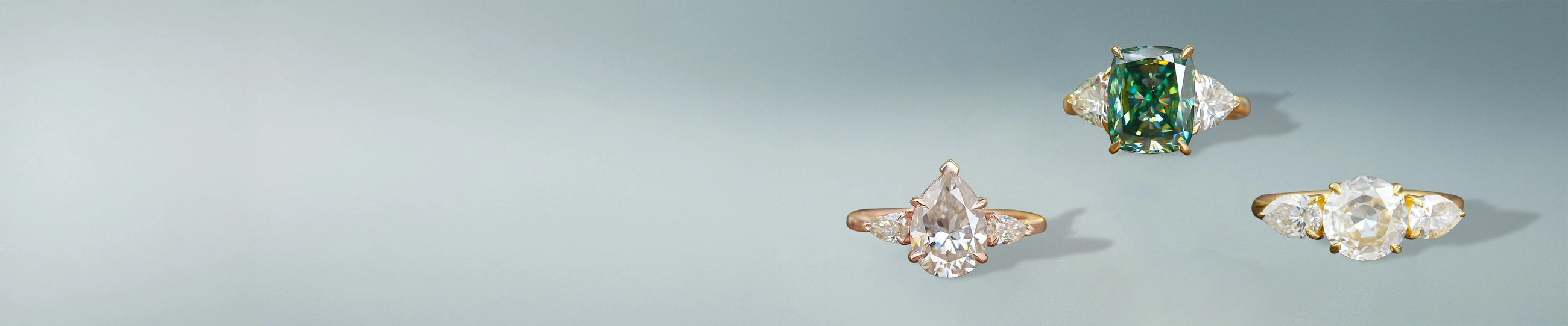 Three stone moissanite rings with pear, round, and emerald cuts in gold and rose gold settings