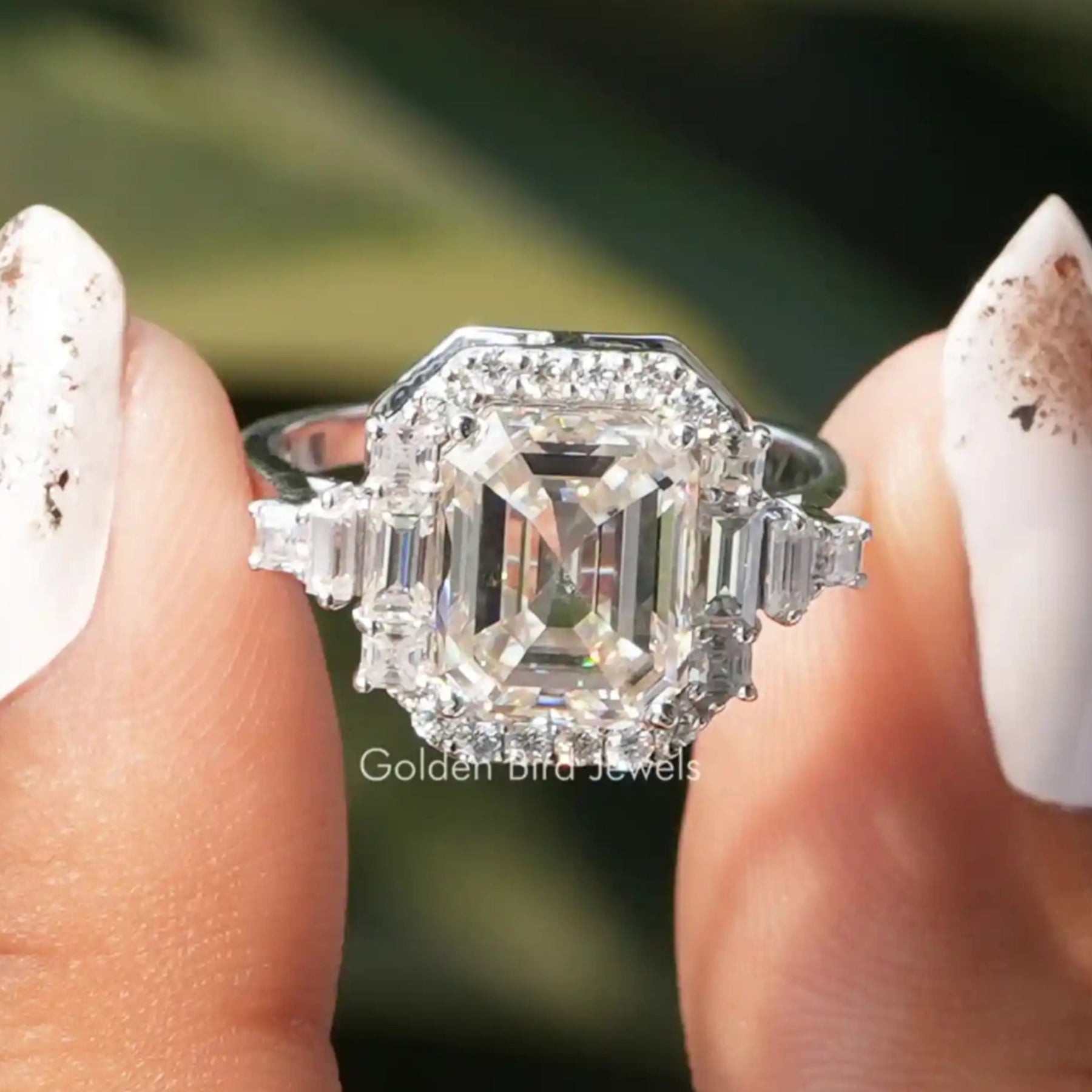 Two fingers holding the Moissanite Asscher Cut Halo Ring