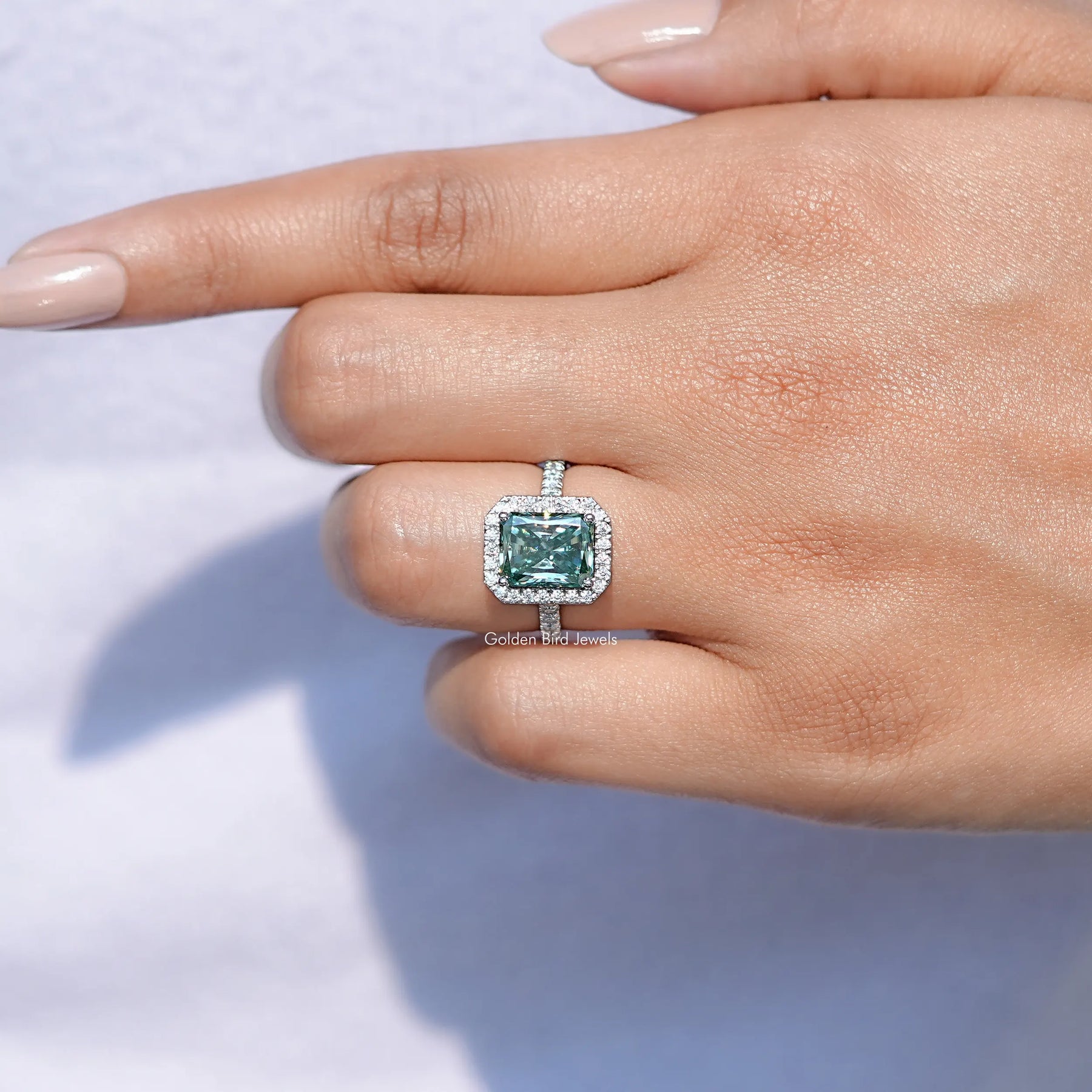 View of solitaire Blue Green Radiant Cut Moissanite ring in prongs setting 