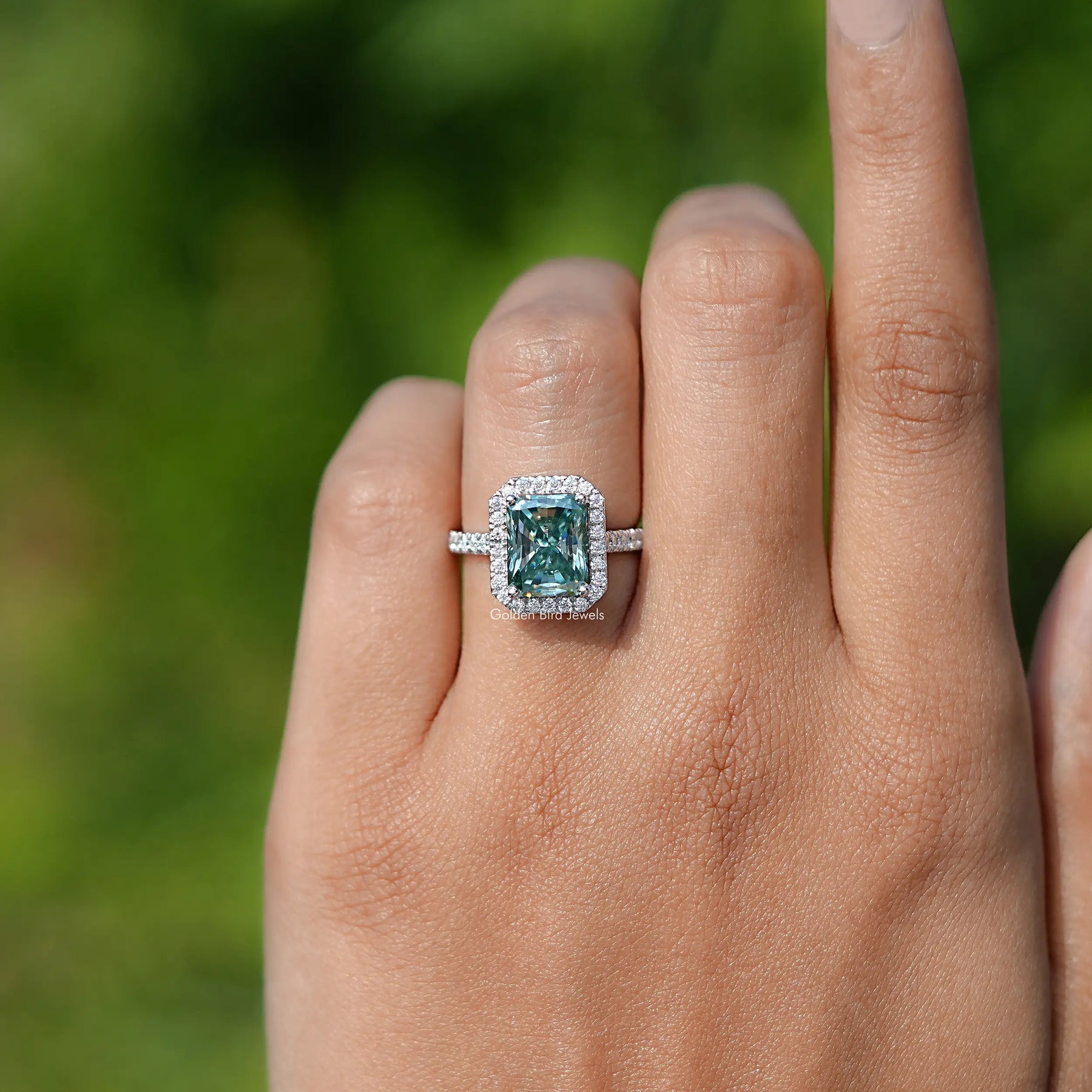 In finger front view of Blue Green Radiant Cut Moissanite engagement ring 
