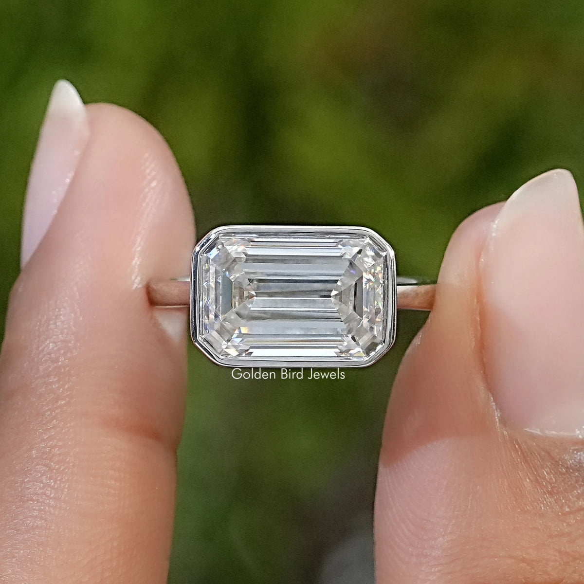 Sterling silver solitaire ring with a clear, elongated emerald-cut stone in a bezel setting