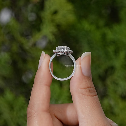 Silver ring shown from the side, with a raised emerald-cut center stone and halo setting