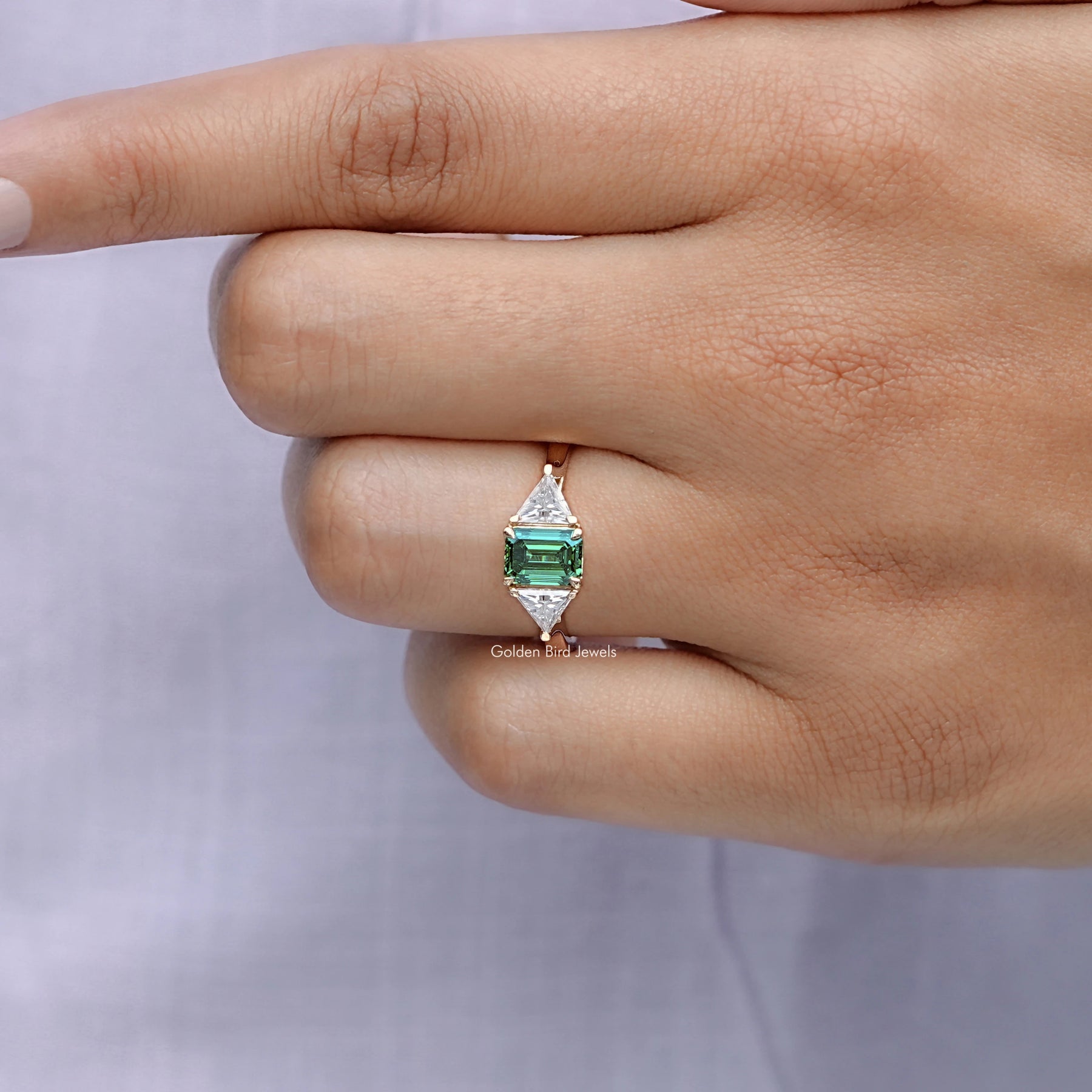 View of solitaire Emerald And Triangle Moissanite Three Stone Ring in prongs setting 