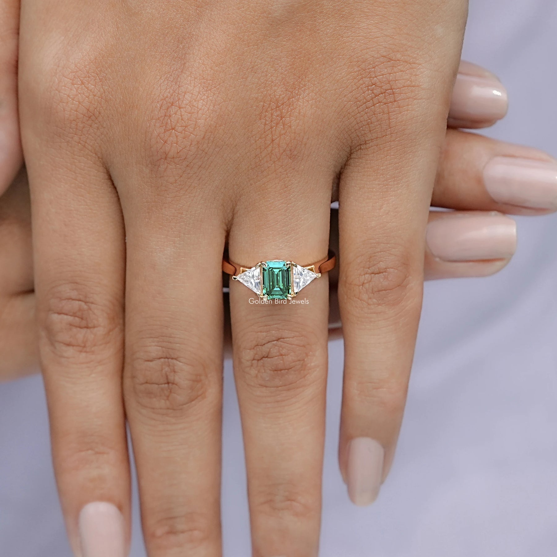 Close view of Emerald And Triangle Moissanite Three Stone Ring
