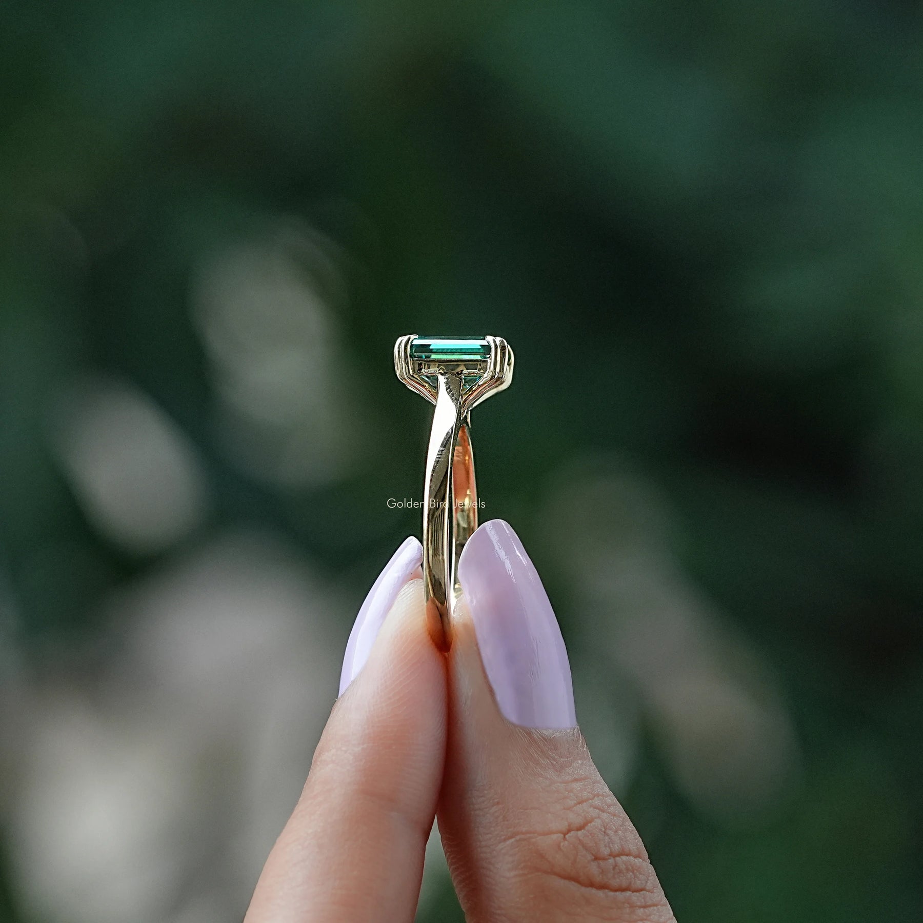 Side view of moissanite ring holding on two fingers 