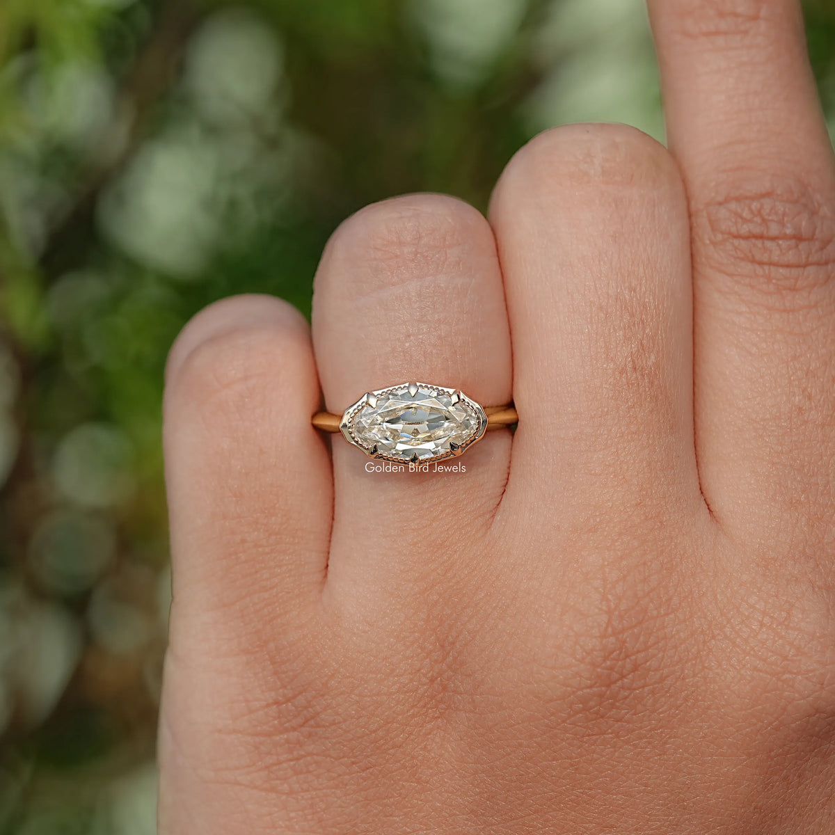 Gold-tone oval solitaire ring with faceted center stone, side view on fingers