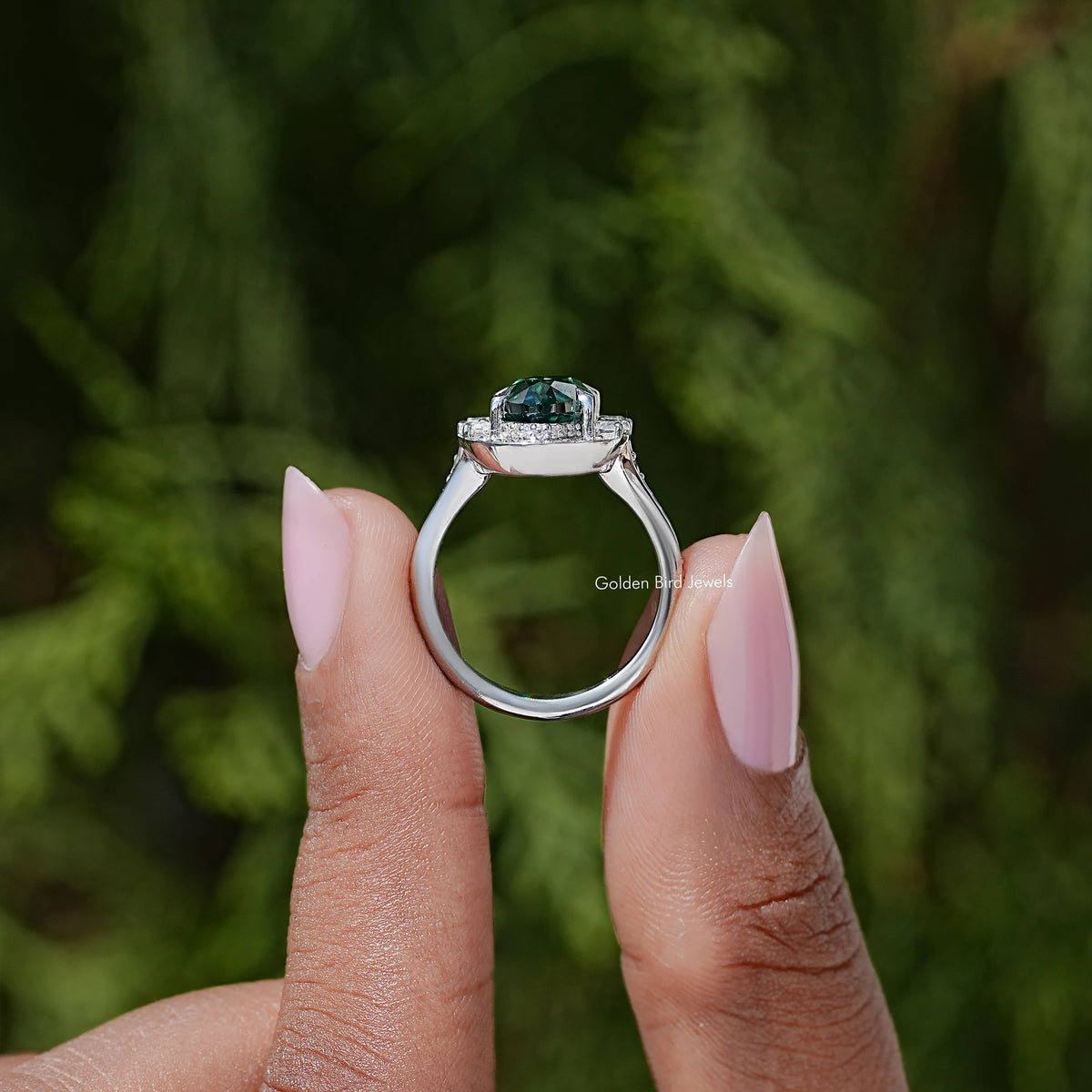 Side view of silver halo ring showing dark green oval gemstone and gallery